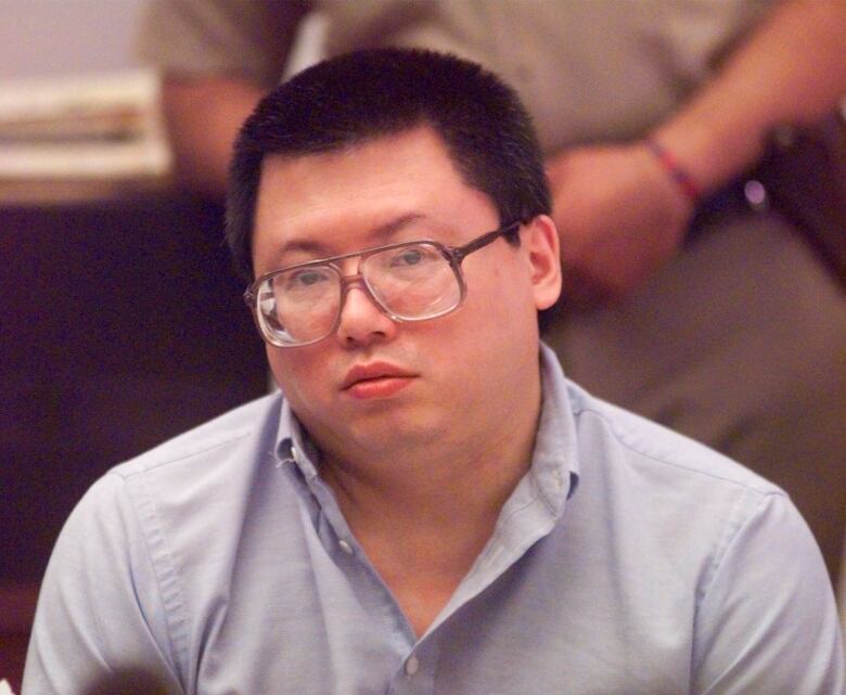 A bespectacled man in a collared shirt is shown in court in an archival photo.