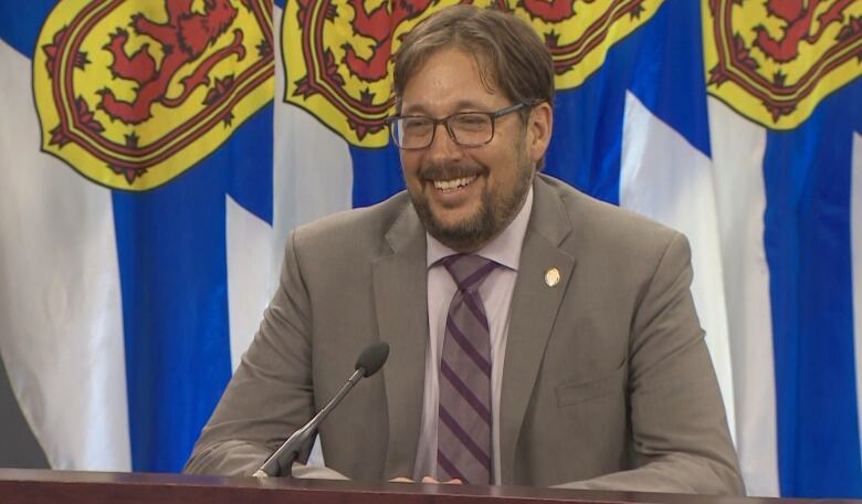 A man with a beard and glasses sits at a table.