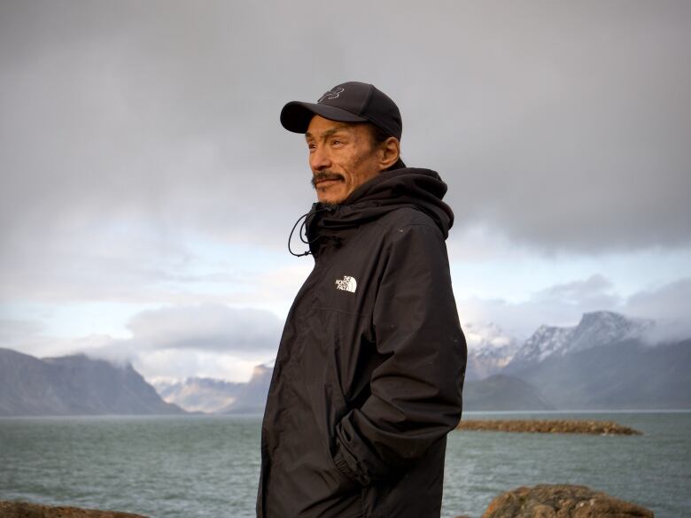 Robert stands in front of the ocean facing west.