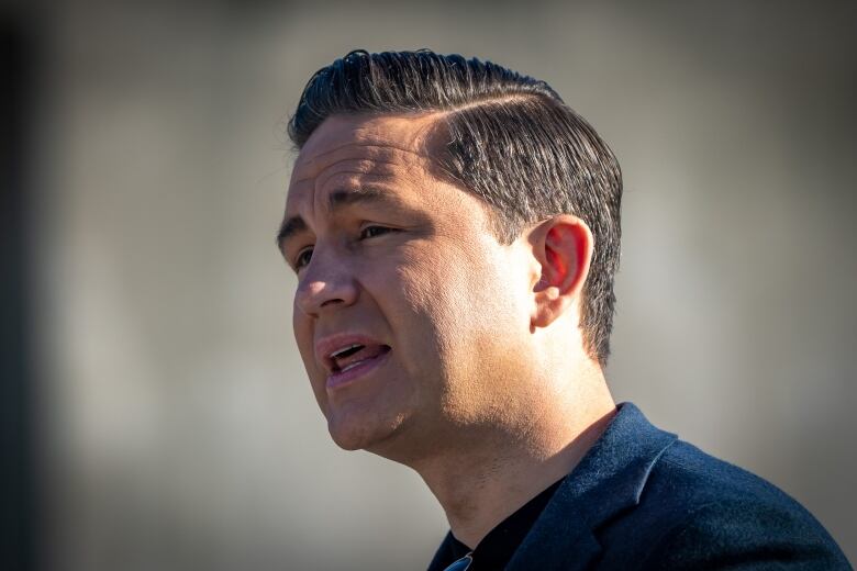 A headshot of a man in a blue suit as he speaks at a podium that is out of view.