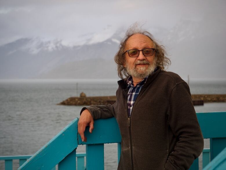 Marcus leaning against a railing with the ocean behind him.