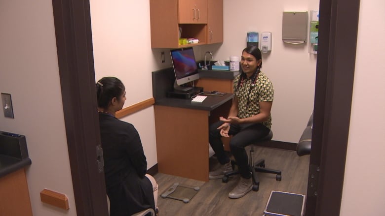 A doctor speaks to someone in a clinic room