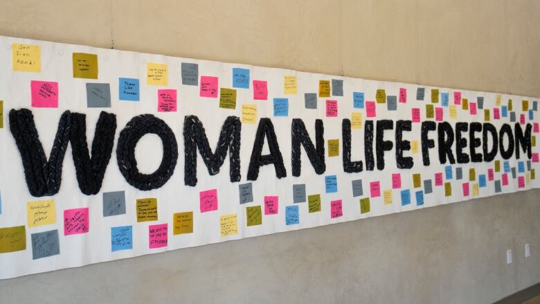 A wide banner on display says Woman Life Freedom in bold black letters