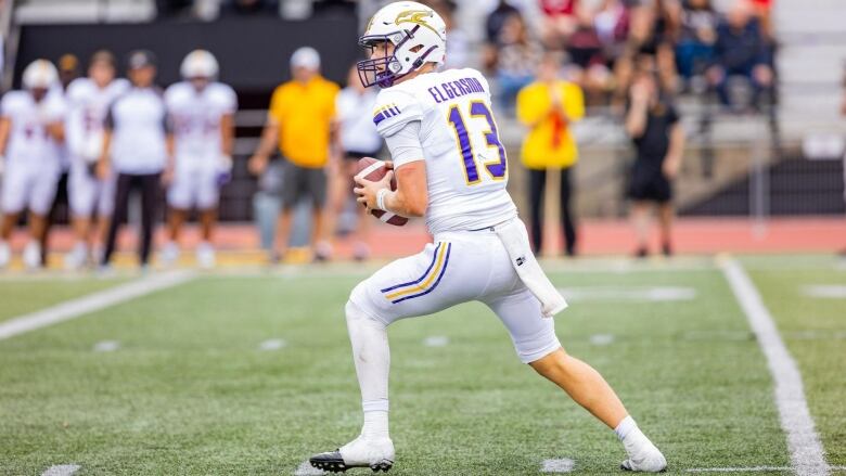 A football player in a white jersey looks to make a throw.