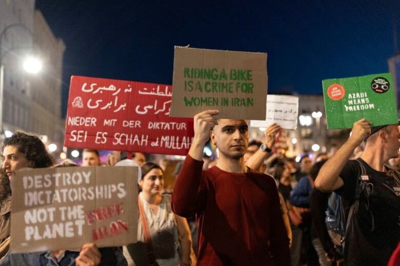 Protesters hold signs as they march at night.