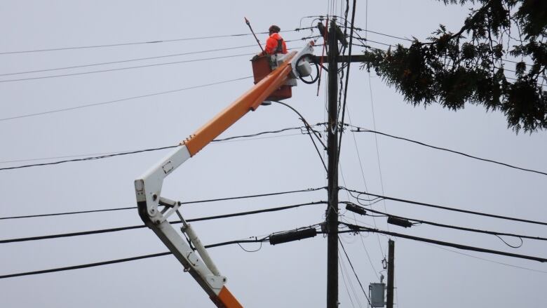 Man at the top of a bucket truck, fixing power lines. 