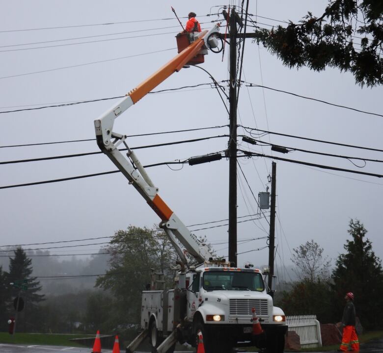 Man at the top of a bucket truck, fixing power lines. 