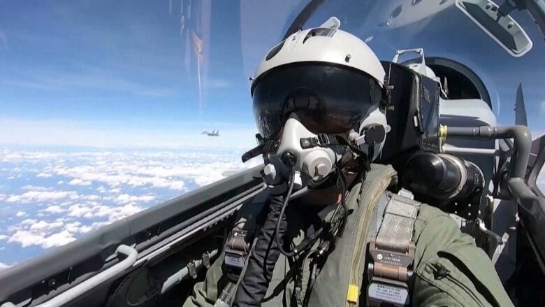 A fighter pilot is seen in a plane as it flies.