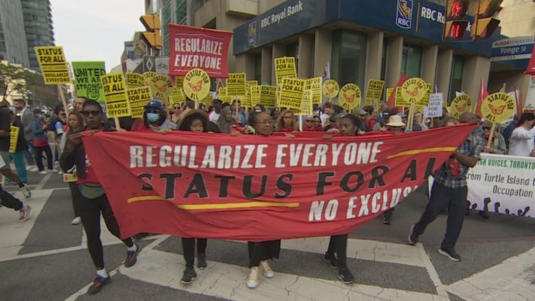 People hold signs and march through an intersection.