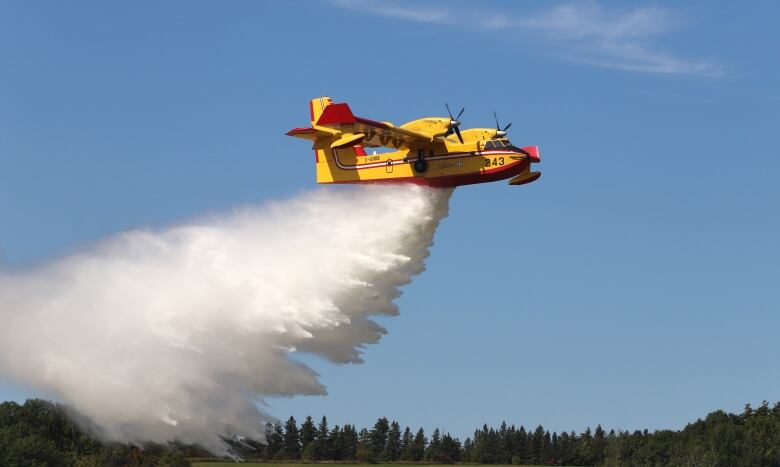 A water bomber dumps some water as it flies.