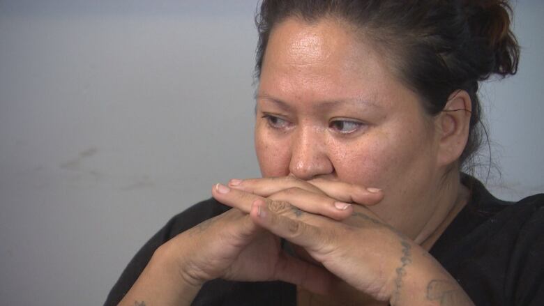 A portrait of a woman with her hands clasped by her chin