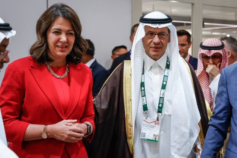 A woman wearing red and a man in white stand together.