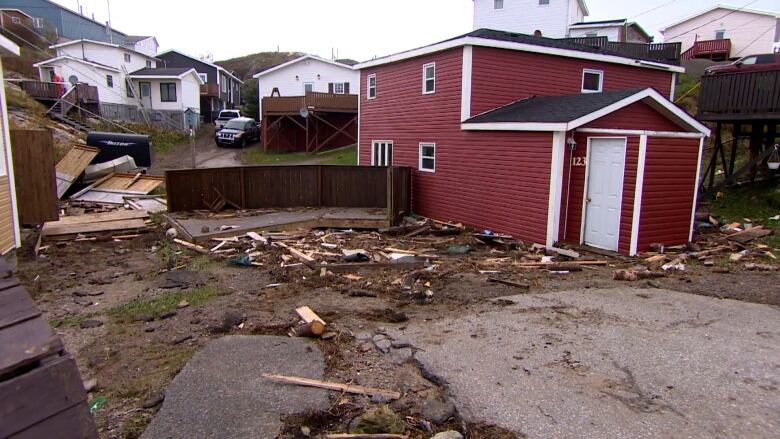 A home sits off centre on the ground. Broken pieces of wood are scattered all over the ground.