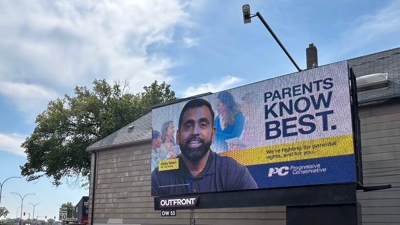 A billboard featuring the face of a Obby Khan with the words 