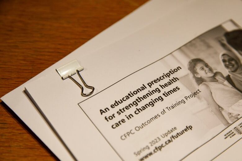 Sheets of paper are held together with a white paperclip, sitting on a desk. The first page reads: 'An educational prescription for strengthening health care in changing times: CFPC outcomes of training project.'