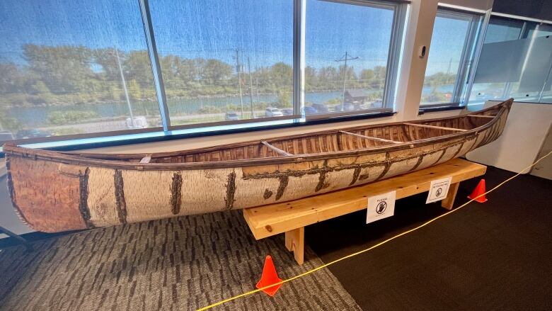 A birchbark canoe sitting by a window in an office space.