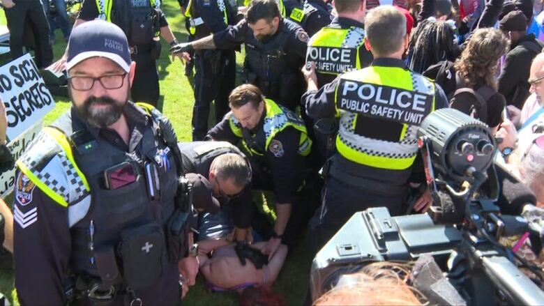 Police surround a person on the ground with their hands behind their back