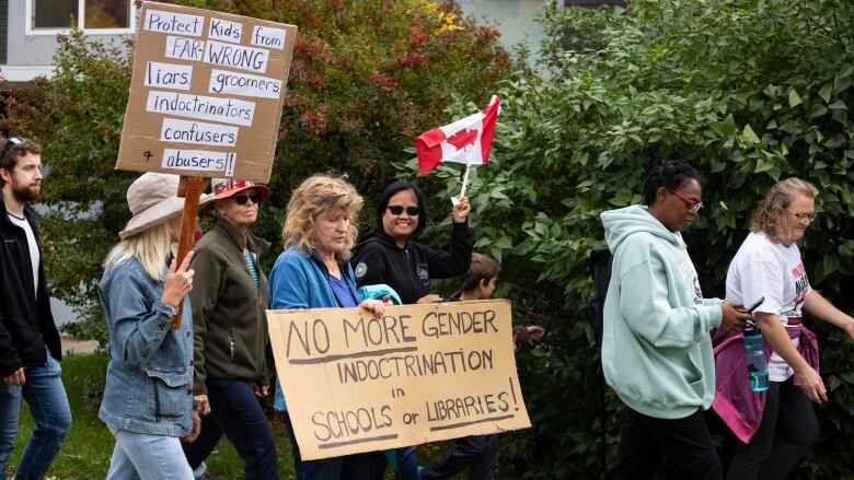 A group marches holding signs at a protest.