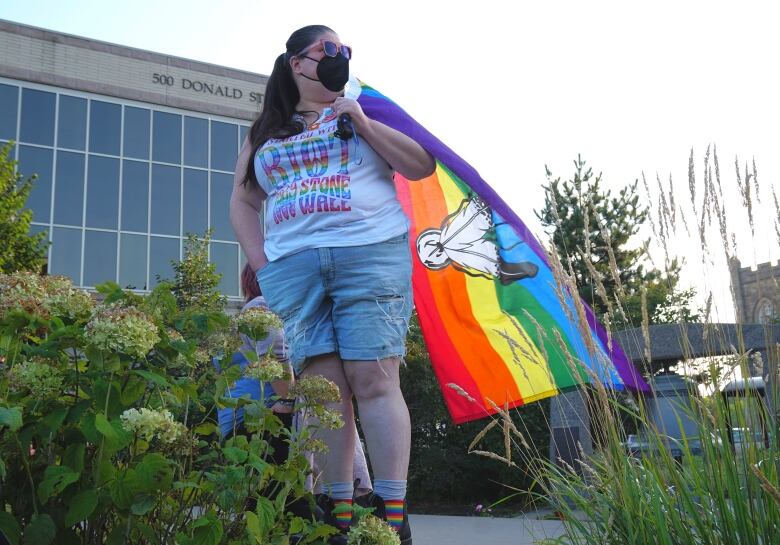 A person holds a rainbow-coloured flag.