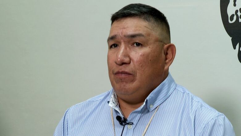 A portrait of a man looking at the camera wearing a blue button-up shirt.