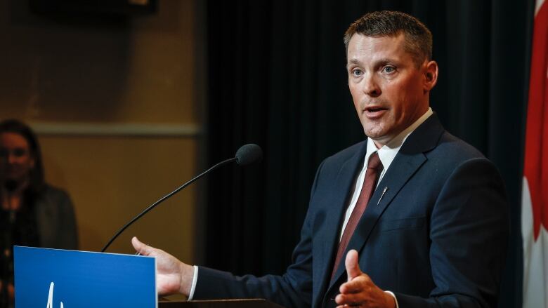 A man speaks behind a podium.