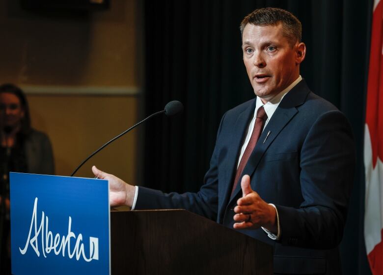 A man speaks behind a podium.