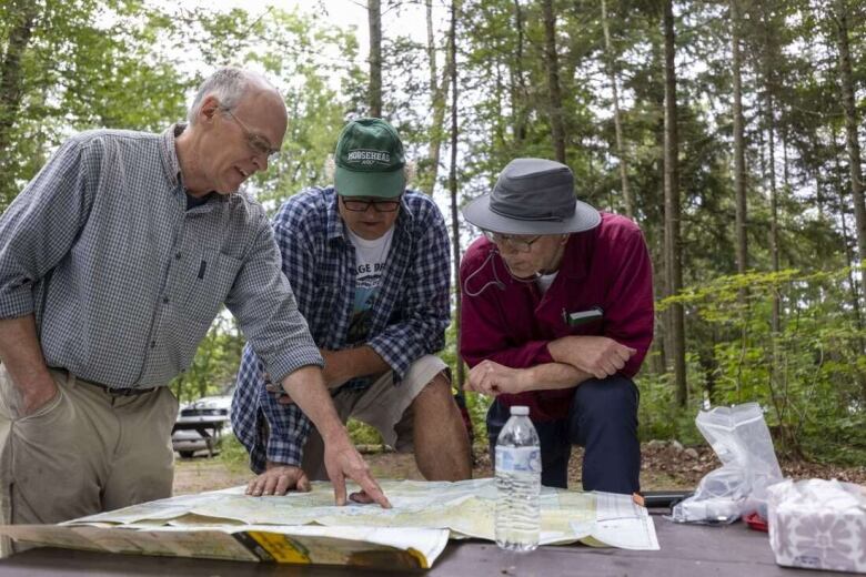 Three men look at a map.