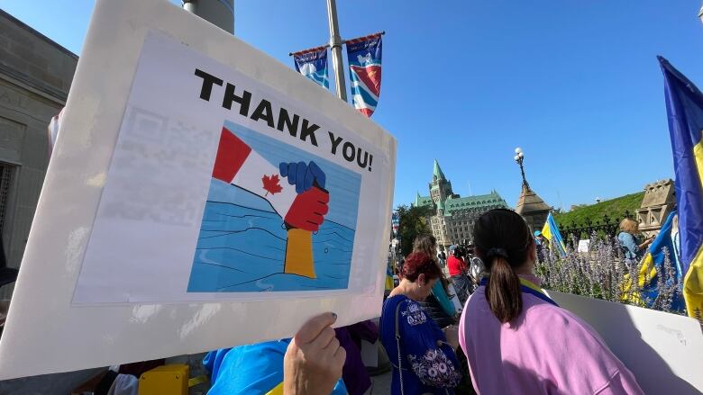 A woman in front of Parliament Hill holds a sign in support of the relationship between Canada and Ukraine. Dozens of people from the Ukrainian community lined the streets of Wellington Friday to support President Vlodimir Zelenskyy's visit to Canada.