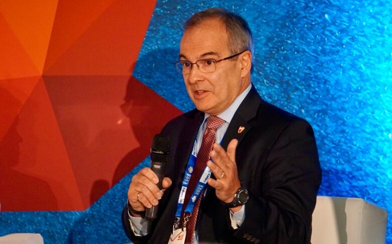 An executive speaks into a microphone while on stage at an oil conference.