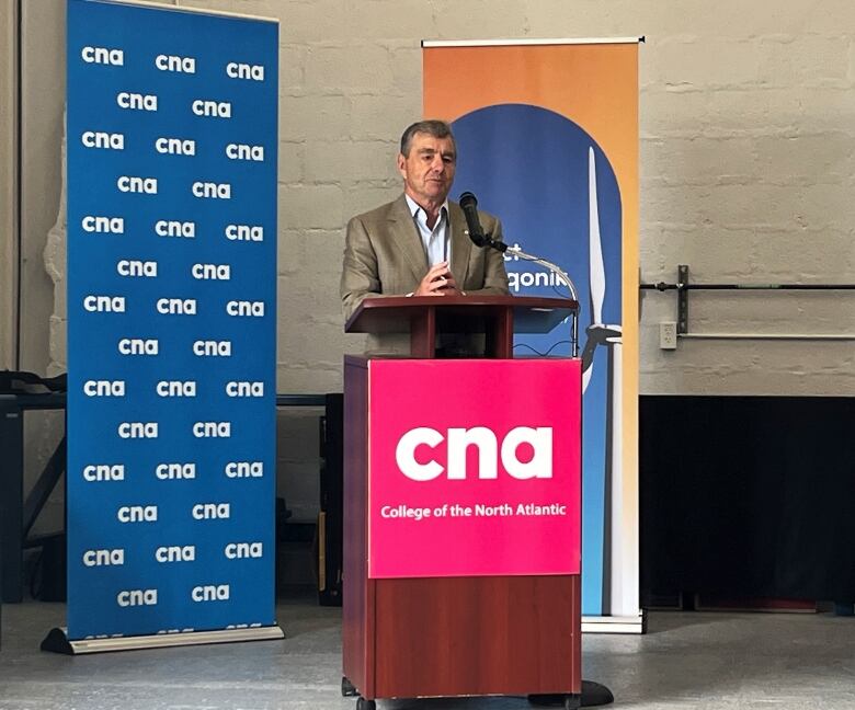 Man in suit behind podium with sign saying CNA