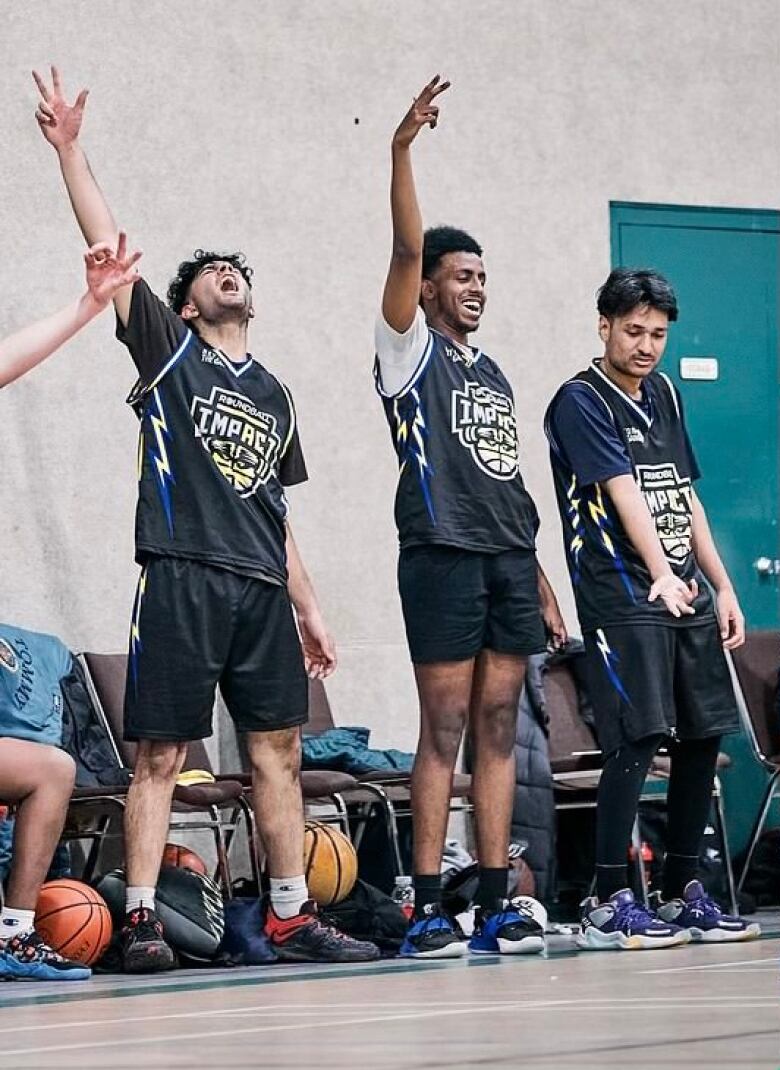 Basketballers raise their hands in celebration on the sidelines.