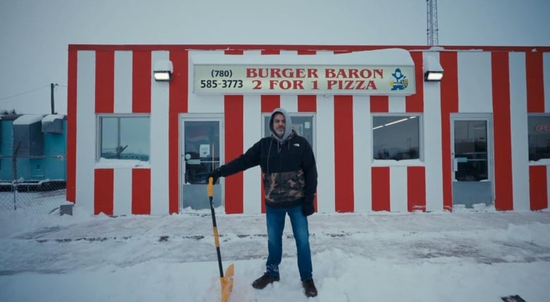 A man is pictured in front of a restaurant in the snow.