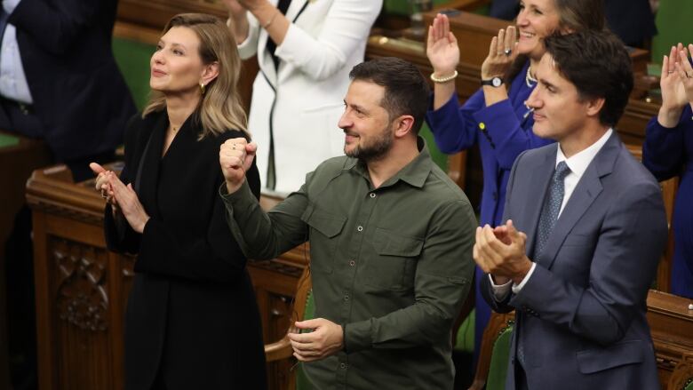 People applaud and smile while looking upward.