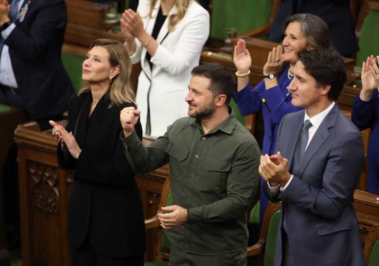 People applaud and smile while looking upward.