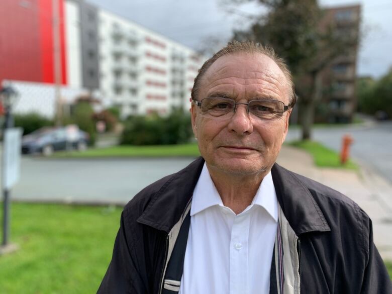 A man stands on a sidewalk in front of apartment buildings. The man is Kevin Russell, the executive director of the Investment Property Owners Association of Nova Scotia (IPOANS). 