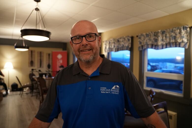 A smiling man wearing polo shirt. The shirt features a logo for the town of Channel-Port aux Basques.