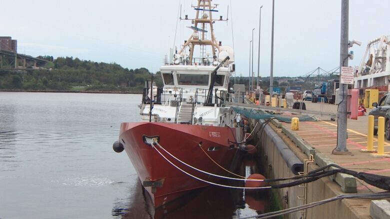 A red ship tied up at a wharf.