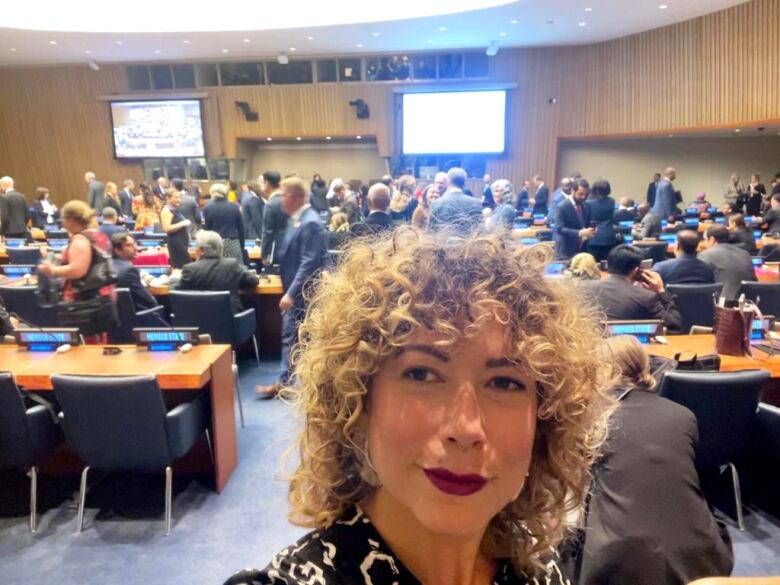 A woman with curly hair is shown in a selfie.