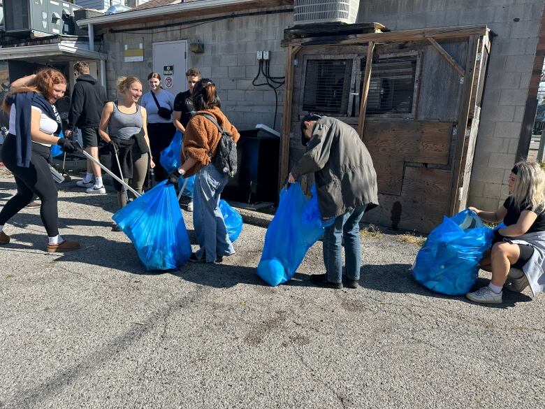 Western University students clean up the aftermath of this year's unsanctioned street party near Broughdale Avenue. 