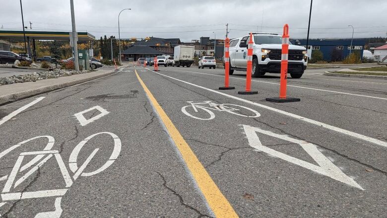 A bike lane with cars and trucks driving by.