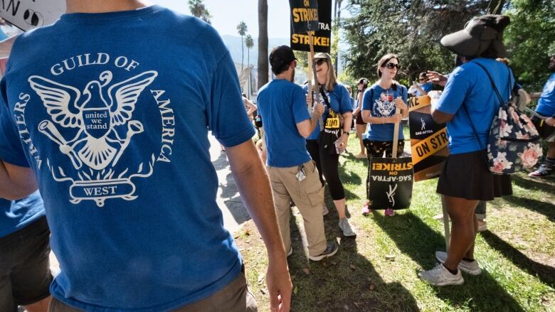 A group of striking writers stand with picket signs.