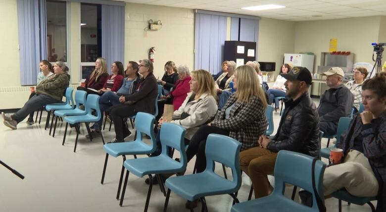 A group of adults sitting inside a classroom. 