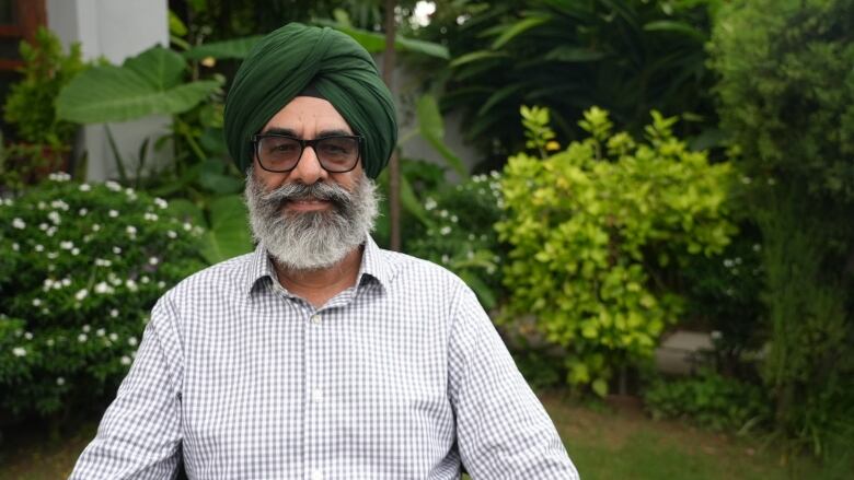 A person sits in front of lush greenery.