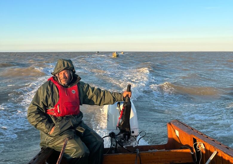 Cree man steering a fishing boat on the water. 