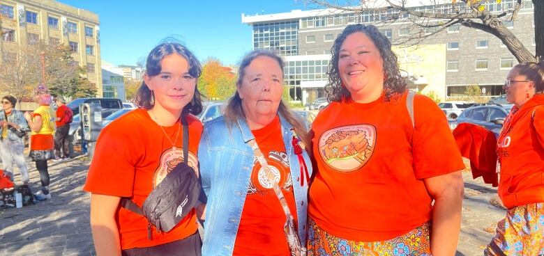 Three women stand together. 