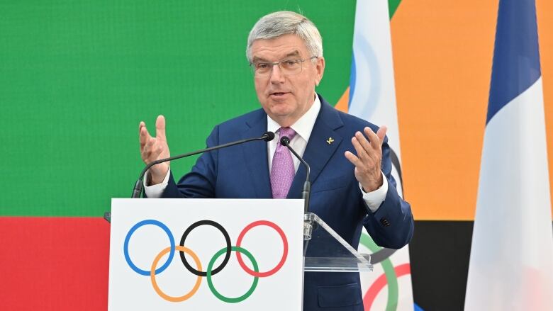 A man wearing a suit speaks behind a podium.