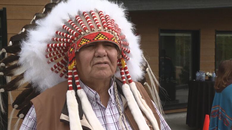 A man in a headdress looks into the camera.  