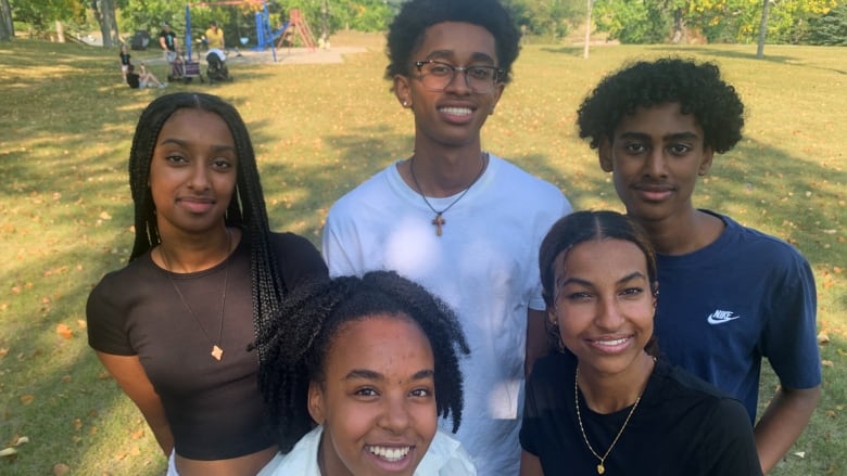 A group of five high school students pose in a park