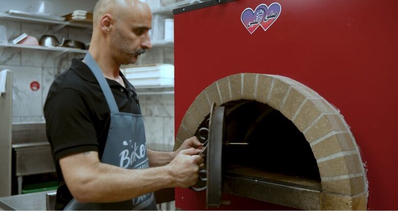 A baker opens an oven in a Desi store. Many stores sell ready to eat meals and freshly baked specialty naan breads.