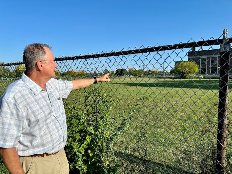 A man points across a vacant school yard.